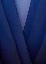 Blusa de manga larga con diseño degradado en tonos azules. Presenta un tejido fluido y semitransparente, con un elegante cuello cruzado y corte recto.