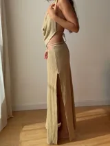 Falda larga tejida color marrón con brillo metálico, corte al cuerpo, abertura alta en la pierna y recortes laterales con cordones ajustables.