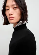 Sweater de punto fino color negro, con cuello perkins, diseño entallado y manga larga.