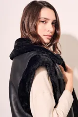 Chaleco negro de cuero sintético con cuello de piel sintética y cierre frontal con cremallera.