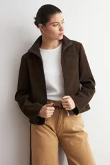 Chaqueta de cuero color marrón oscuro, con cuello alto, cierre frontal y diseño minimalista de corte recto.
