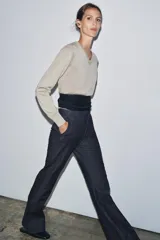 Jeans de tiro medio con corte flare y largo completo. Presenta bolsillos delanteros, cierre con cremallera, botón y ganchos metálicos.