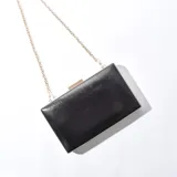 Sobre negro rígido con cierre dorado y cadena dorada desmontable.