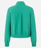 Campera bomber femenina color beige claro, confeccionada en tejido Airflow texturado. Presenta cuello solapa, cierre frontal de cremallera y puños y bajo elásticos.