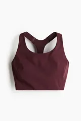 Top deportivo color vino tinto, de tejido funcional con tecnología ShapeMove™ y DryMove™, corte ajustado, escote cuadrado al frente y espalda nadadora en malla con cut-out. Presenta copas forradas con relleno extraíble y breteles anchos ajustables.