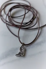 Dije de acero quirúrgico con forma de bota de estilo cowboy, con detalles grabados en relieve.