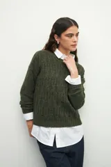 Sweater de tejido tramado en color verde oliva, con cuello redondo y mangas largas. Presenta un diseño de textura acanalada vertical.