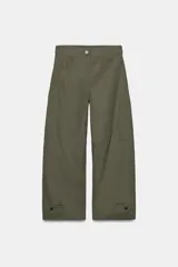 Pantalón de tiro alto en color verde militar, con corte barrel de pernera holgada que se estrecha hacia el tobillo. Presenta trabillas laterales ajustables en la cintura y en el bajo, bolsillos delanteros y cierre frontal con cremallera y botón.