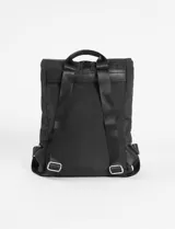 Mochila de tela negra con diseño de solapa superior y cierre de mosquetón. Cuenta con un bolsillo frontal vertical con cierre, asa superior y correas ajustables.