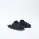 Pantuflas tipo mule de color negro, confeccionadas en material aterciopelado con detalle de borde en pelo sintético. Poseen suela plana y diseño abierto en el talón.