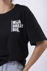 Remera negra de corte oversize con estampado frontal que dice "MIJA DREAM BIG" en tipografía blanca y rosa.
