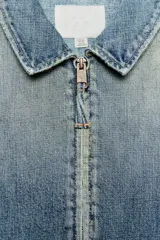 Chaqueta de denim con efecto lavado, cuello solapa, manga larga y cierre frontal con cremallera metálica.