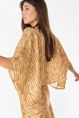 Blusa de lino italiano color blanco, con diseño holgado, escote asimétrico estilo off-shoulder y mangas cortas amplias.