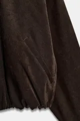 Cazadora bomber de Zara, de color bordó, con cuello de solapa, manga larga, bolsillos de vivo en el delantero y bajo elástico. Cuenta con cierre frontal de cremallera metálica.