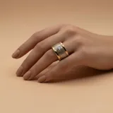Anillo ancho de diseño mixto en plata y oro, con una banda central texturizada y una circonia engastada en el centro.