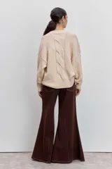 Sweater de punto en color beige, con cuello redondo acanalado, mangas largas con puños ajustados y diseño holgado.