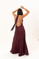 Vestido largo de color bordó con escote en V profundo y diseño de espalda descubierta. Presenta un corte fluido con falda amplia y caída suave.