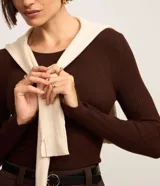 Suéter de punto acanalado color beige, con cuello redondo y mangas largas. Confeccionado en tejido tricot con textura suave y ajuste al cuerpo.