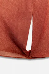 Top de punto color naranja con cuello polo, escote en V y mangas largas amplias con bajo abullonado.