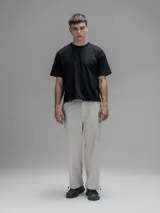 Pantalón cargo de corte oversize confeccionado en microfibra elastizada color beige. Presenta cintura elástica, bolsillos laterales y un bolsillo cargo con cierre de broche a presión. Incluye un sistema de elásticos con tancas en los tobillos para ajustar la apertura.