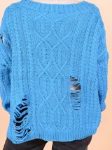 Cárdigan tejido de punto grueso color celeste con diseño trenzado y roturas. Tiene cuello en V, cierre frontal con botones y mangas largas.