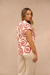 Blusa Magda de manga corta con escote en V y cuello mao. Diseño de corte recto en color blanco con estampado circular en tonos rojos y beige.