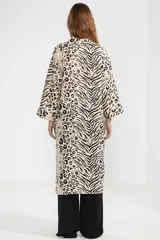 Camisa larga de lino color crema con estampado animal print que combina patrones de leopardo y cebra, cuello en V, cierre frontal con botones y mangas tres cuartos.