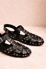 Sandalia tipo guillermina confeccionada en cuero nobuk color chocolate con tachas doradas y hebilla lateral.