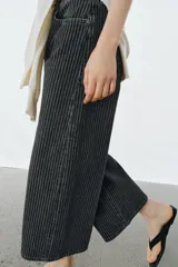 Jeans de tiro medio con diseño culotte y pierna ancha. Presenta un estampado de rayas verticales a contraste, cinco bolsillos, trabillas en la cintura y cierre frontal con cremallera y botón.