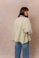 Camisa lila de calce relajado y manga larga, con cuello clásico, puños y bolsillo delantero en denim contrastante. Cierre frontal con broches metálicos.