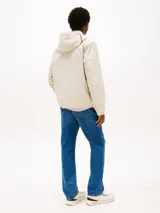 Campera con capucha de poliéster reciclado, color beige claro, con cierre frontal y puños elásticos. Presenta detalles en los colores de la marca en el cuello y un logo engomado en la manga.