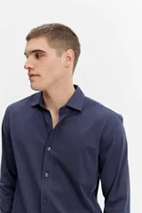 Camisa de manga larga color verde militar, con cuello tradicional y cierre frontal de botones.