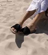 Sandalias de cuero negro con tira ancha de pelo y suela plana de corcho.
