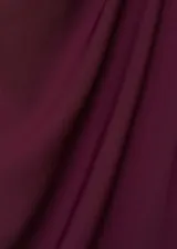 Mono largo color borgoña, con cuello Perkins drapeado, sin mangas, corte recto, cinturón con hebilla y cierre de cremallera en la parte posterior.