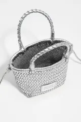 Bolso mini trenzado color dorado, con doble asa corta de mano y correa larga para el hombro. Incluye parche con logo grabado en el frente.