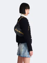 Bolso bandolera Balmain modelo Soft Moon, confeccionado en cuero negro con patrón geométrico en relieve y logo Balmain en letras doradas. Asa de cadena dorada con apliques de cuero negro.