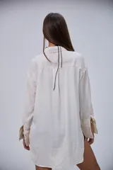 Camisa lisa de corte oversize en color beige, con cuello clásico, mangas largas y puños anchos.