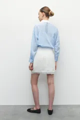 Minifalda de tweed color blanco con flecos en el ruedo.