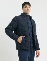 Campera capitoneada de color azul marino, con capucha desmontable, cierre frontal y bolsillos laterales con cierres engomados y tiradores en color naranja.