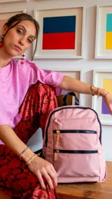 Mochila rosa de tafeta con apertura superior con cierre y tiradores metálicos, bolsillos internos, bolsillo con doble cierre metálico al frente, asas rígidas de mano y correas regulables para colgar en la espalda.