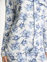 Conjunto de pijama de dos piezas con estampado animal print. La parte superior es una camisa de manga larga con cuello solapa, escote en V, cierre frontal con botones y bolsillo aplicado. El pantalón cuenta con cintura elástica y lazo de ajuste.