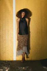 Falda midi de tiro alto con bajo asimétrico y cierre frontal cruzado con botón. Presenta un diseño que combina estampado de lunares y animal print.