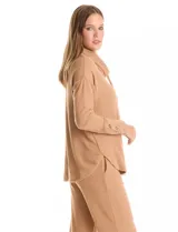 Buzo de tejido suave con cuello volcado ajustable mediante cordones con punteras metálicas. Presenta mangas largas con puños decorados con botones metálicos, hombros caídos y ruedo redondeado con aberturas laterales.