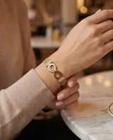 Pulsera de acero con baño de oro, con diseño de símbolo de infinito y barras con circonias en los laterales, tipo malla milanesa.