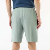 Bermuda de felpa ligera color verde suave, con cintura elástica y bolsillos laterales, de corte cómodo y diseño liso.