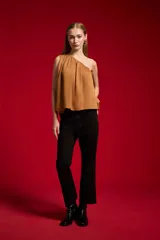 Blusa de poliéster color negro, con diseño asimétrico de un solo hombro, plisado ligero y corte holgado.