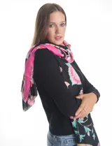 Pashmina estampada con diseño floral en tonos rosados, fucsias y verdes sobre fondo negro. Presenta terminaciones desflecadas en los bordes y está confeccionada en tejido ligero tipo gasa.