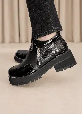 Zapato de cuero color negro con plataforma y suela dentada. Presenta una combinación de texturas que incluye detalles en charol y un sector con textura reptilada, además de cierre lateral y costuras en contraste.