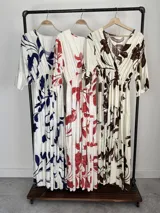Vestido largo color crudo con estampado floral marrón, escote en V cruzado, mangas tres cuartos con volados y falda con niveles fruncidos.
