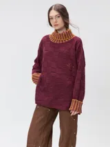 Pullover de punto jacquard con diseño de cuadros en relieve, cuello alto y mangas largas. Presenta detalles de pespuntes en color rojo en el cuello y los puños, aberturas laterales y logo bordado en el pecho.